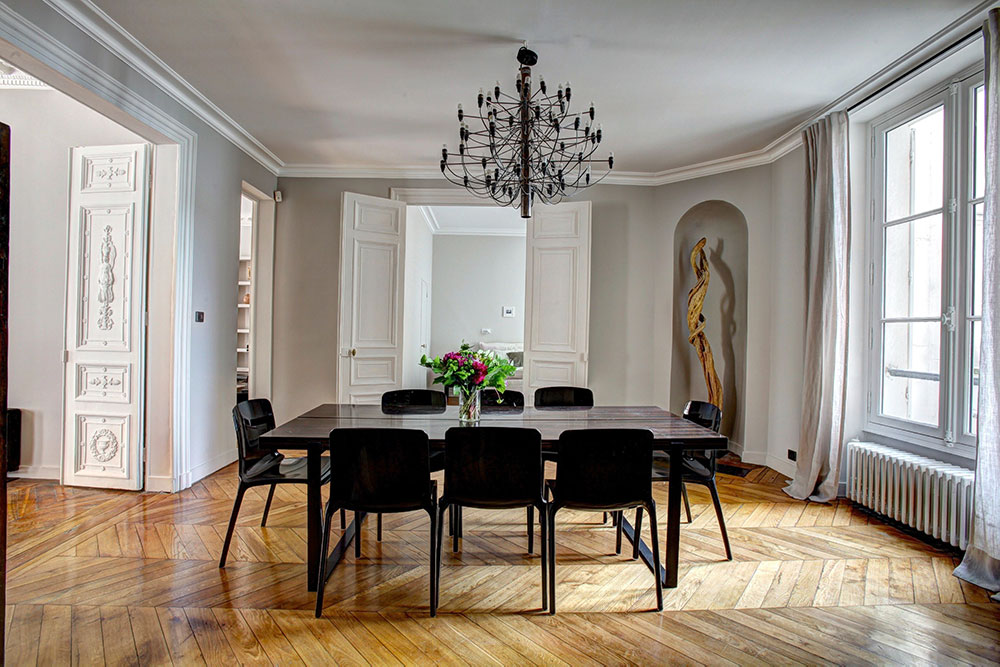 Image of a dining room table and chairs upon a parkay floor with a chandelier above