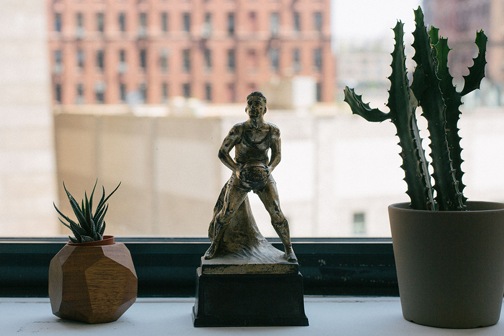 Image of a statue of a young person playing basketball surrounded by cacti