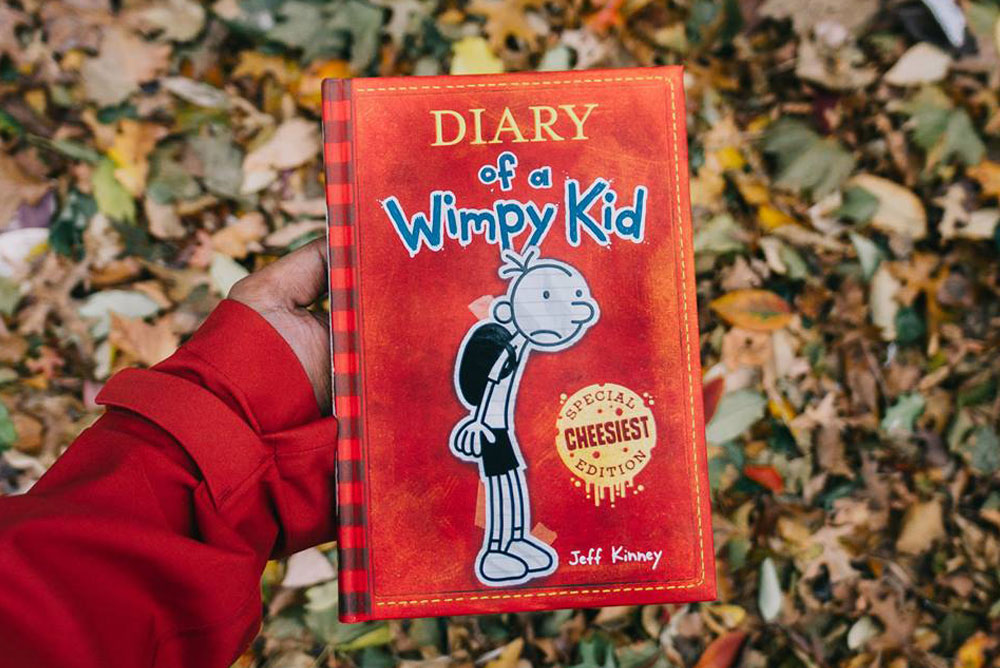 Image of Wimpy Kid book against a backdrop of leaves