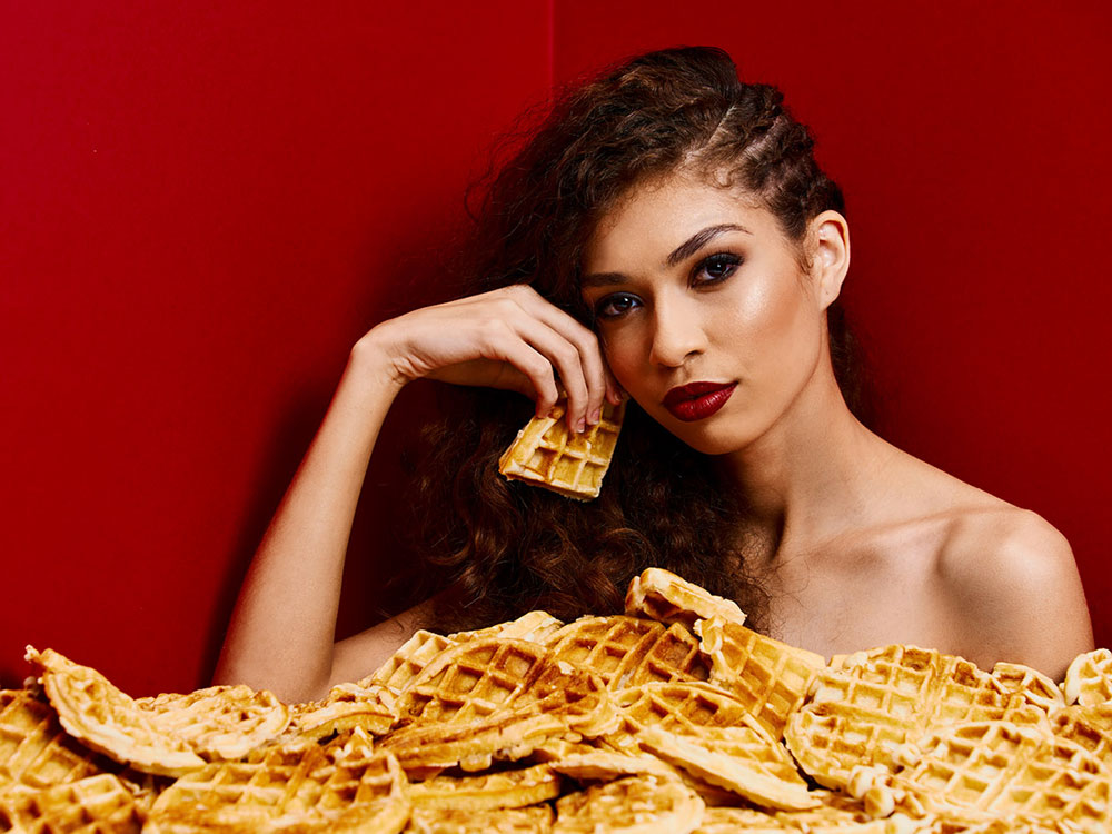 Image of model sitting in a bath of waffles