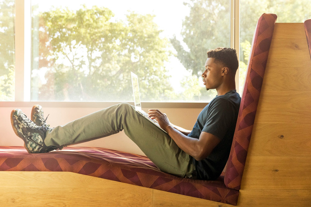 Man reclining on the comfy sofa working on laptop