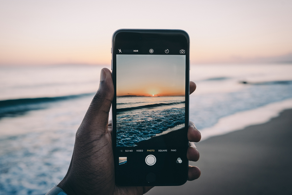 Image of a person taking a picture of a sunset with an iPhone