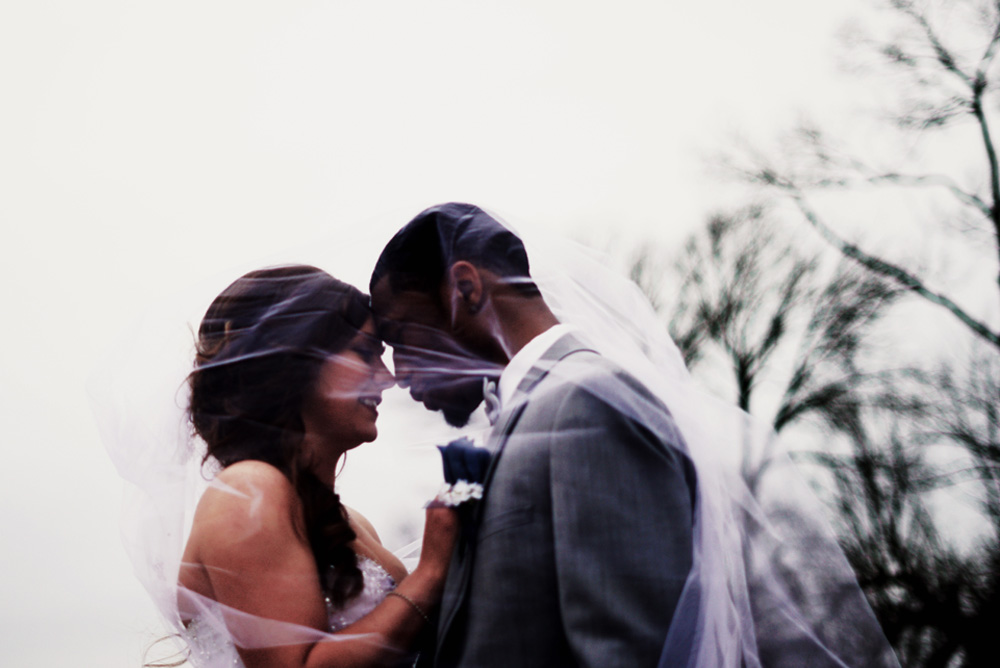 Bride and groom kiss under veil