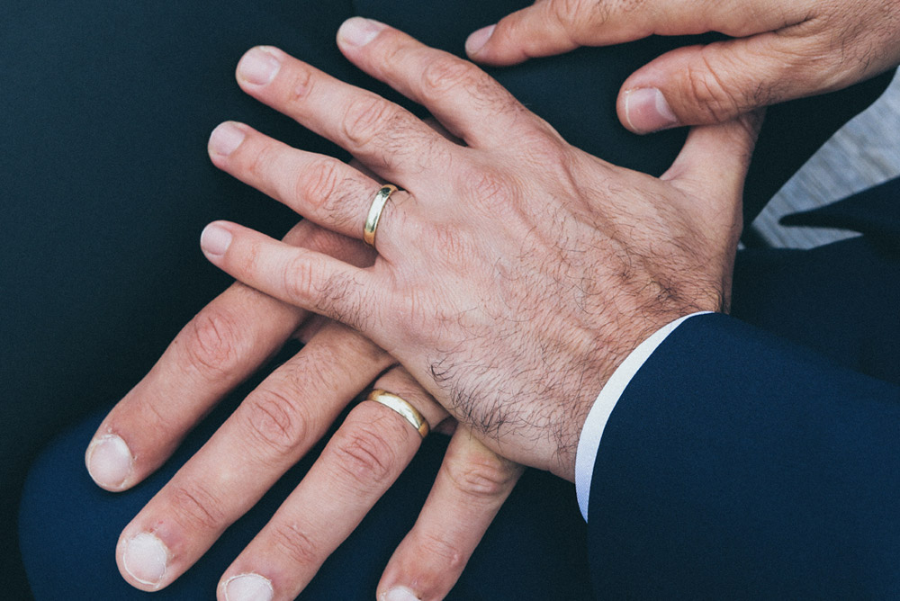 Image of two men holding hands with wedding rings