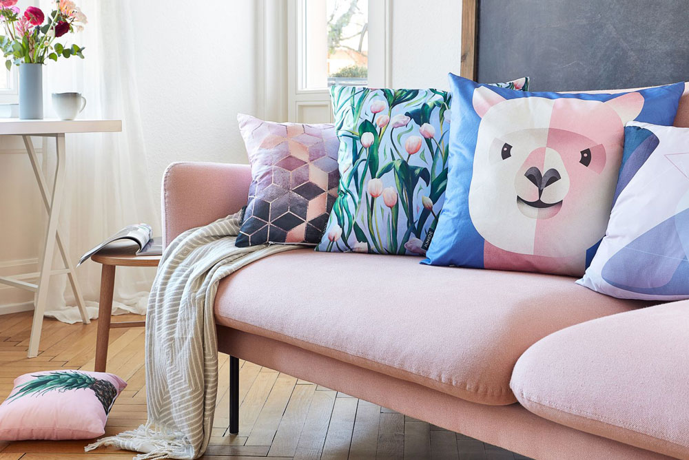 Image of a pink sofa covered in artistic throw pillows