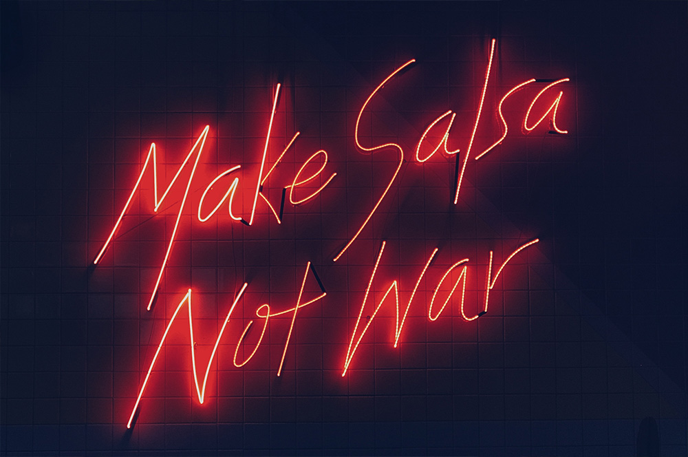 Neon sign saying 'Make salsa not war'