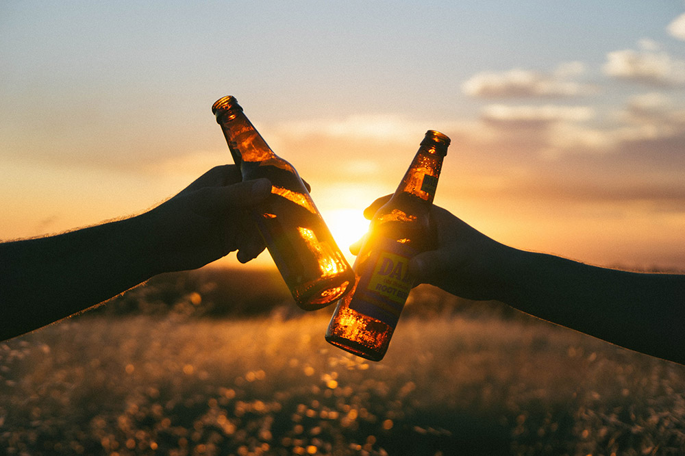 Image of people clinking beer bottles in the sunset