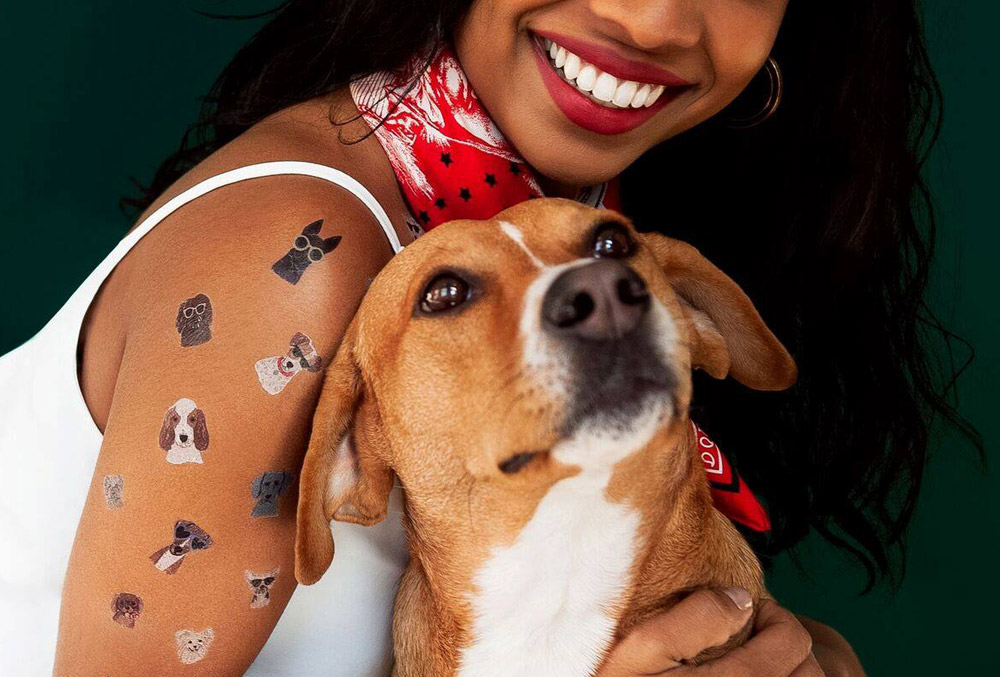 Image of woman with Tattly tattoos of dogs cuddling a real dog